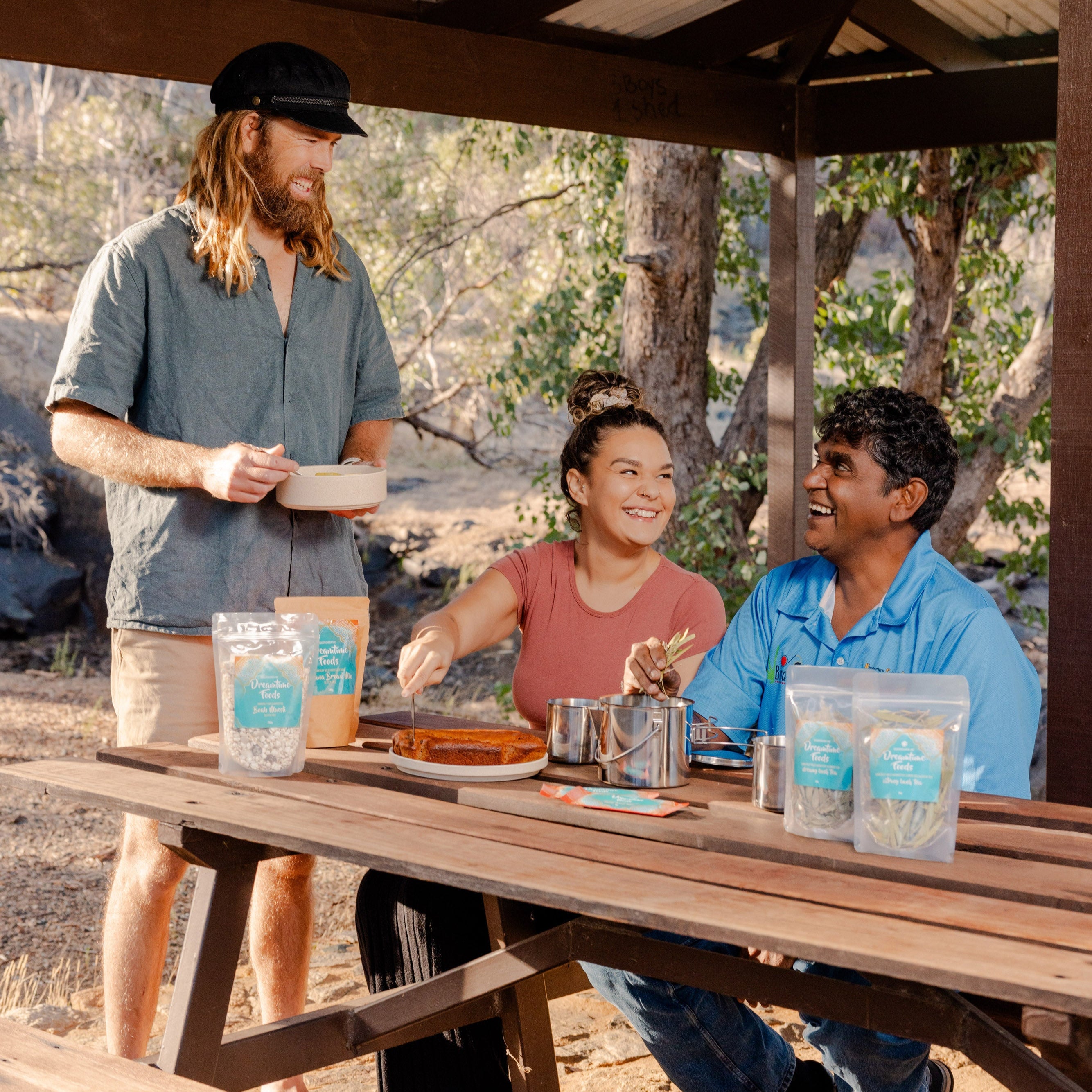 Three people sitting at a picnic table outdoors, enjoying a meal together.